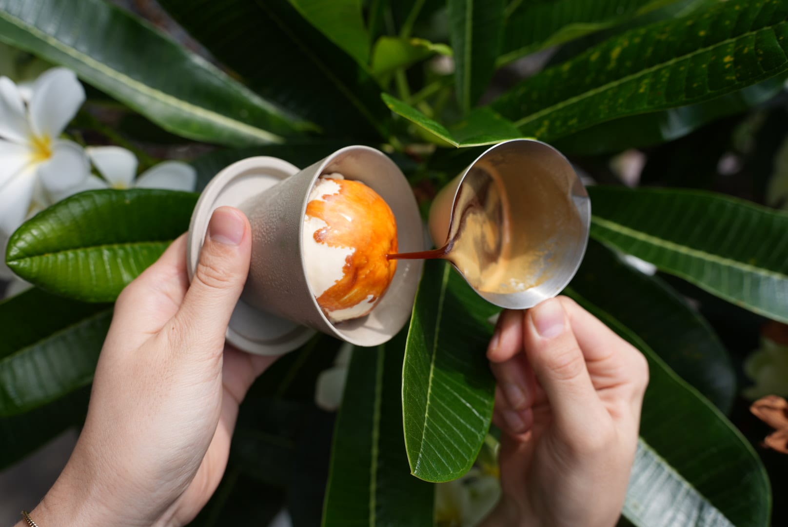 Hands pouring an espresso shot over gelato — the garden affogato